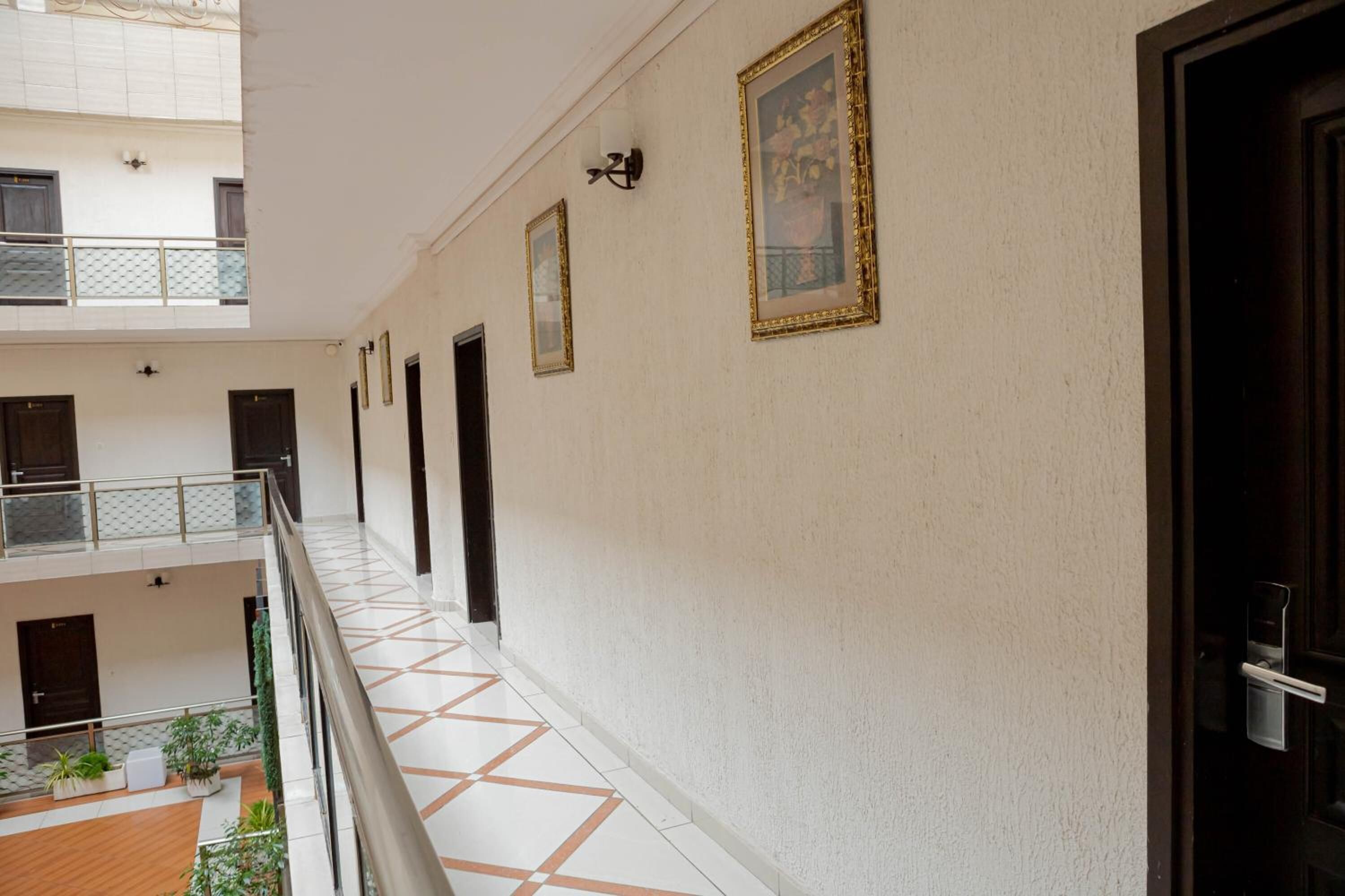 Ein Korridor mit Fliesenboden, einem Balkon mit Geländer und einer Tür rechts.