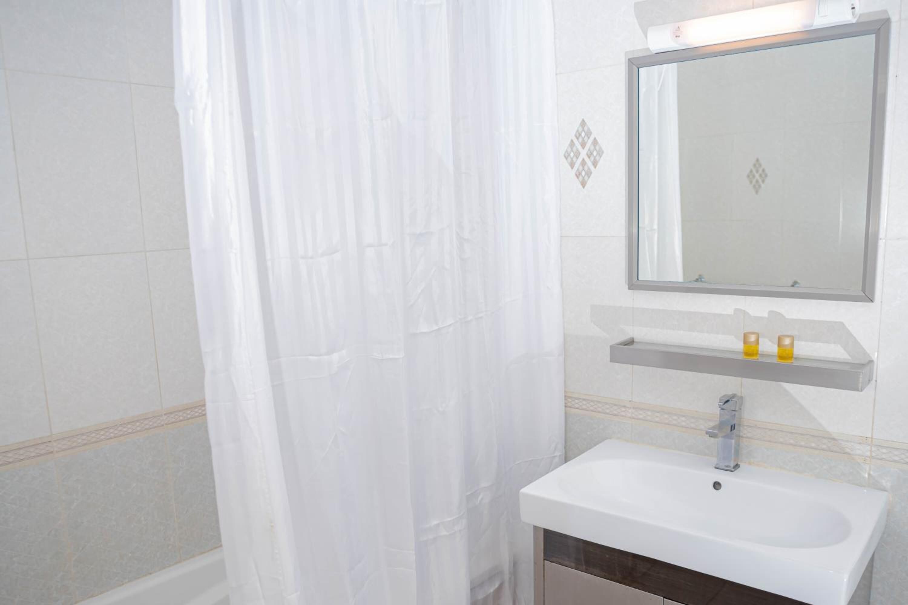 Ein Badezimmer mit weißem Waschbecken, einem Spiegel und einer Duschvorhang.
