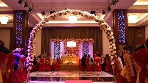 A wedding ceremony with a floral arch and a stage with a lit backdrop. - Hotel Hibiscus Louis (Libreville)