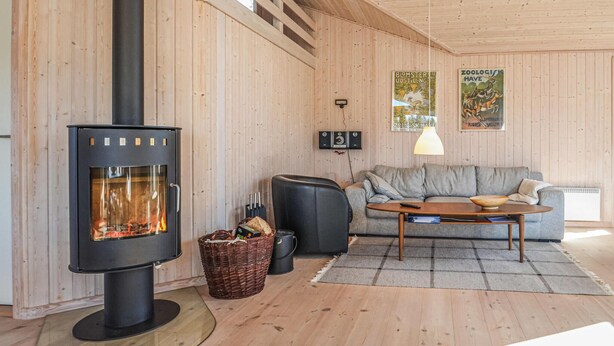 Ett mysigt vardagsrum med en vedeldad kamin, en soffa, ett soffbord och en väggmonterad lampa.