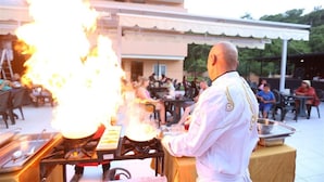 A chef performing a fire-based cooking demonstration outdoors with a crowd watching. - Monna Roza Beach Resort Hotel (Kemer)