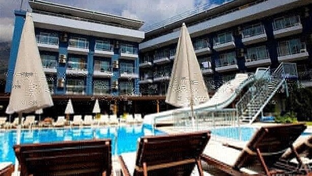 A hotel with a swimming pool, lounge chairs, and umbrellas. - Monna Roza Beach Resort Hotel (Kemer)