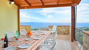 Comedor con una mesa preparada para cuatro personas, con vistas panorámicas al mar.