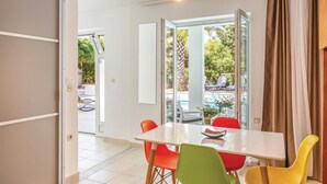 A dining area with a white table and colorful chairs, large windows, and a view of outdoor seating.