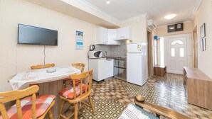 A compact kitchen with a dining area, a flat-screen TV, and a patterned floor. - Nice apartment in Okrug Gornji with WiFi (Okrug Gornji)