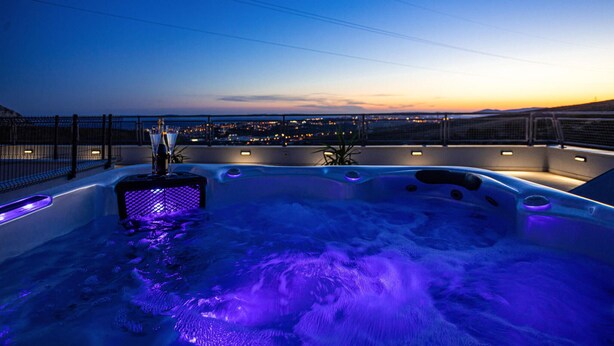 A hot tub with a city view at dusk. - Cozy home in Zrnovnica (Zrnovnica)