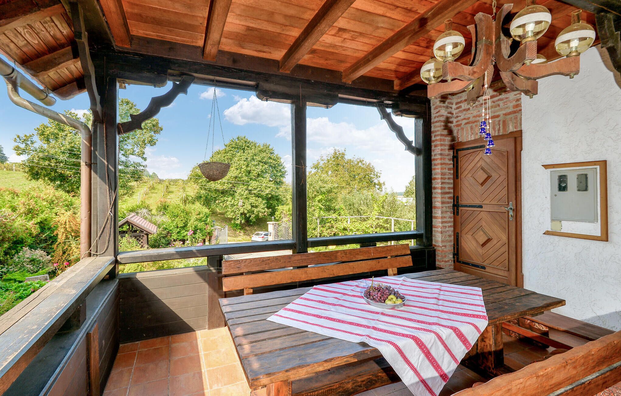 A wooden deck with a bench and a table covered with a striped tablecloth.