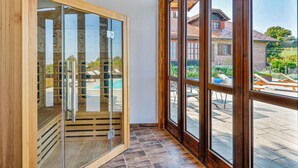 Une pièce dotée d’une grande porte-fenêtre coulissante donnant sur un espace extérieur avec une piscine et des chaises longues.