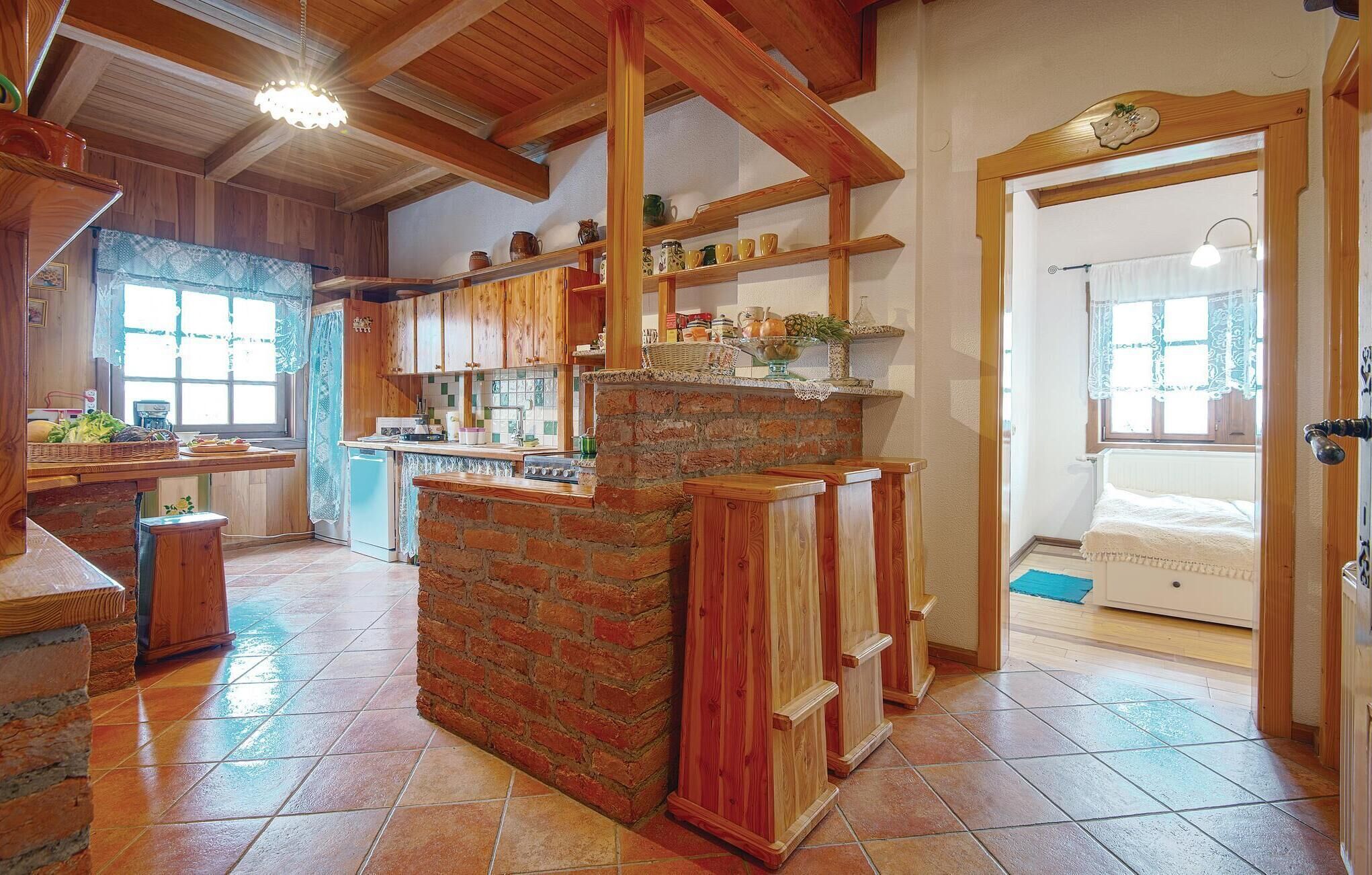 A rustic kitchen with wooden beams, a brick island, and a tiled floor.