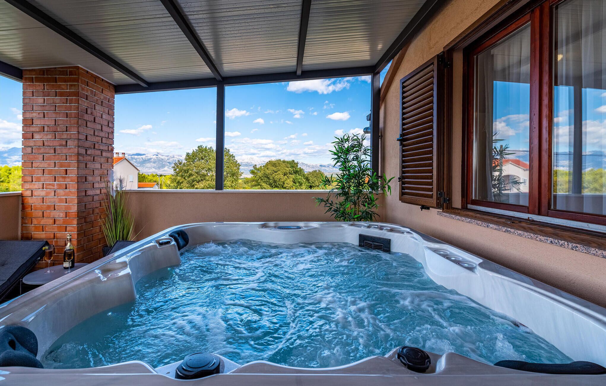 Ett bubbelbad på en balkong med utsikt över berg och träd.