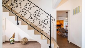 A staircase with ornate metal railings, a dining area with chairs, and a kitchen visible in the background. - Amazing home in Pridraga (Pridraga)
