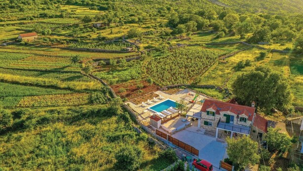 En villa med swimmingpool, omgivet af terrasserede marker og et bjerglandskab.