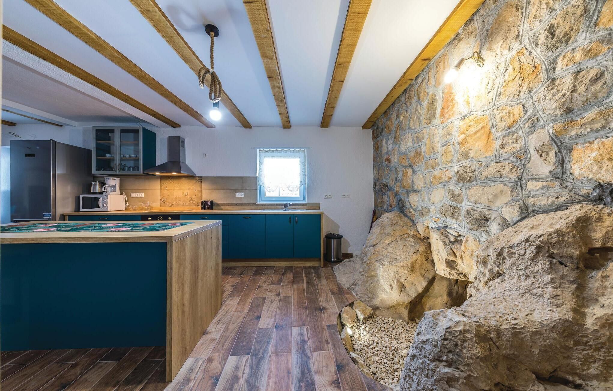 Eine Küche mit Holzbalken, einer Steinwand und einem Fenster.