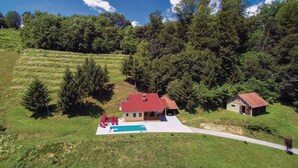 A house with a red roof, a swimming pool, and a small shed.