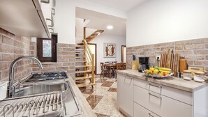 A modern kitchen with a gas stove, sink, and a dining area with a wooden table and chairs.