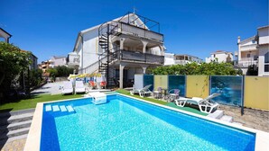 A two-story building with a pool area, including a pool, lounge chairs, and a covered seating area. - 2 bedroom gorgeous apartment in Okrug Gornji (Okrug Gornji)