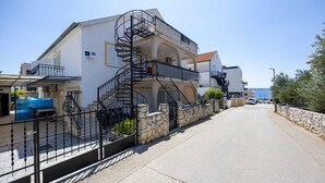 A two-story building with a spiral staircase, stone walls, and a paved street. - 2 bedroom gorgeous apartment in Okrug Gornji (Okrug Gornji)