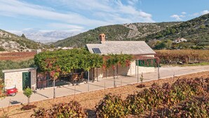 Une maison en pierre avec un toit de tuiles, entourée de vignes et d’un vignoble.