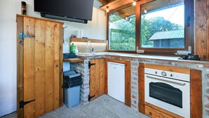 Una cucina compatta con mobili in legno, forno integrato, lavello e finestra con vista sul verde.