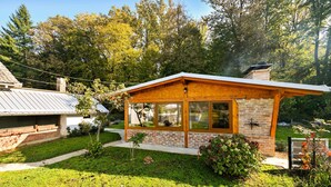 Una piccola casa a un piano con facciata in mattoni, un portico in legno e ampie finestre.