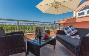 Relax on the balcony with a clear view of the lush landscape, featuring a sofa, armchair, and coffee table.