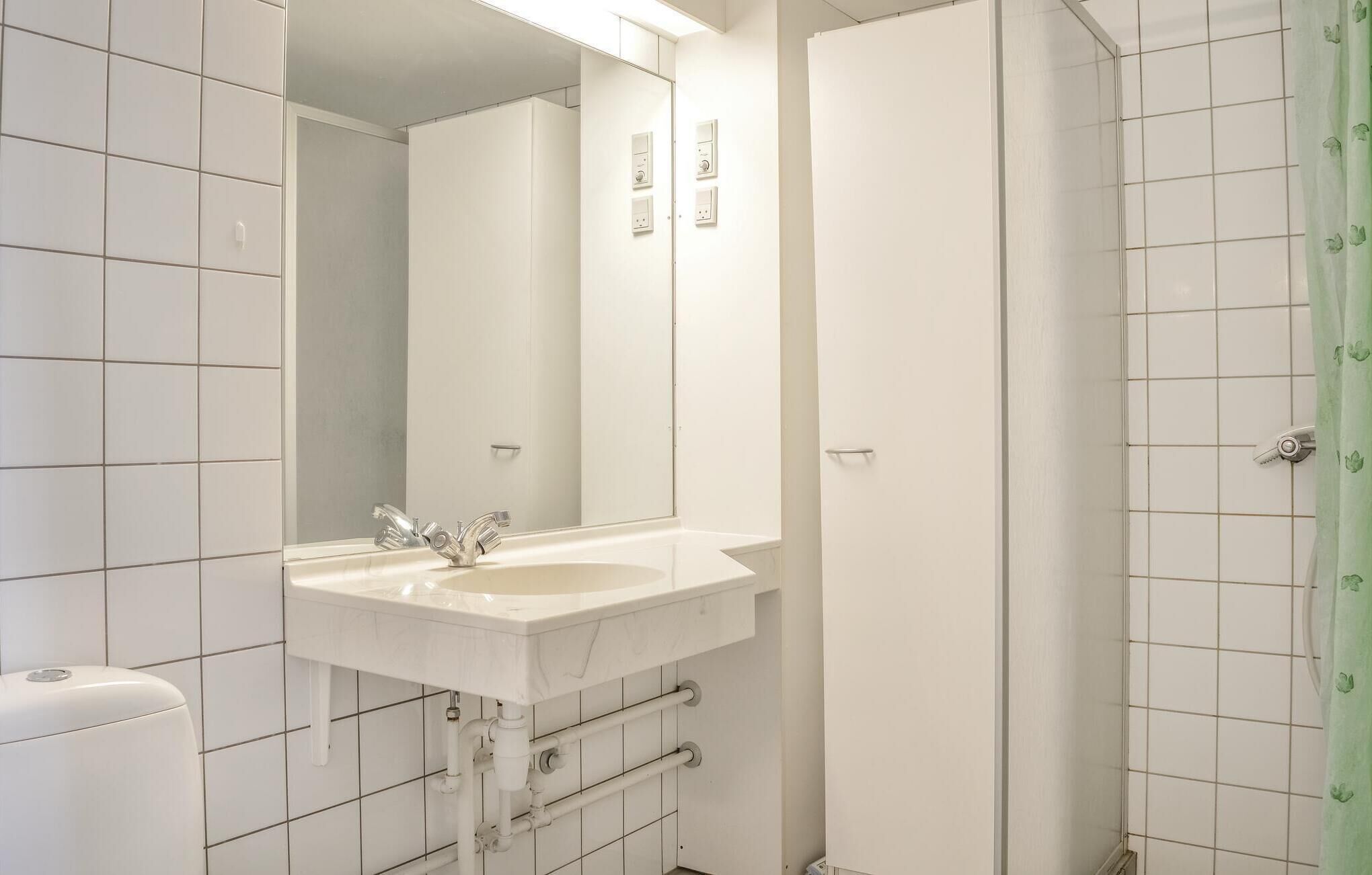 Un bagno con lavandino, specchio e doccia bianchi.