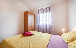 Relax in this serene bedroom with a large bed, a wardrobe, and a bedside lamp.