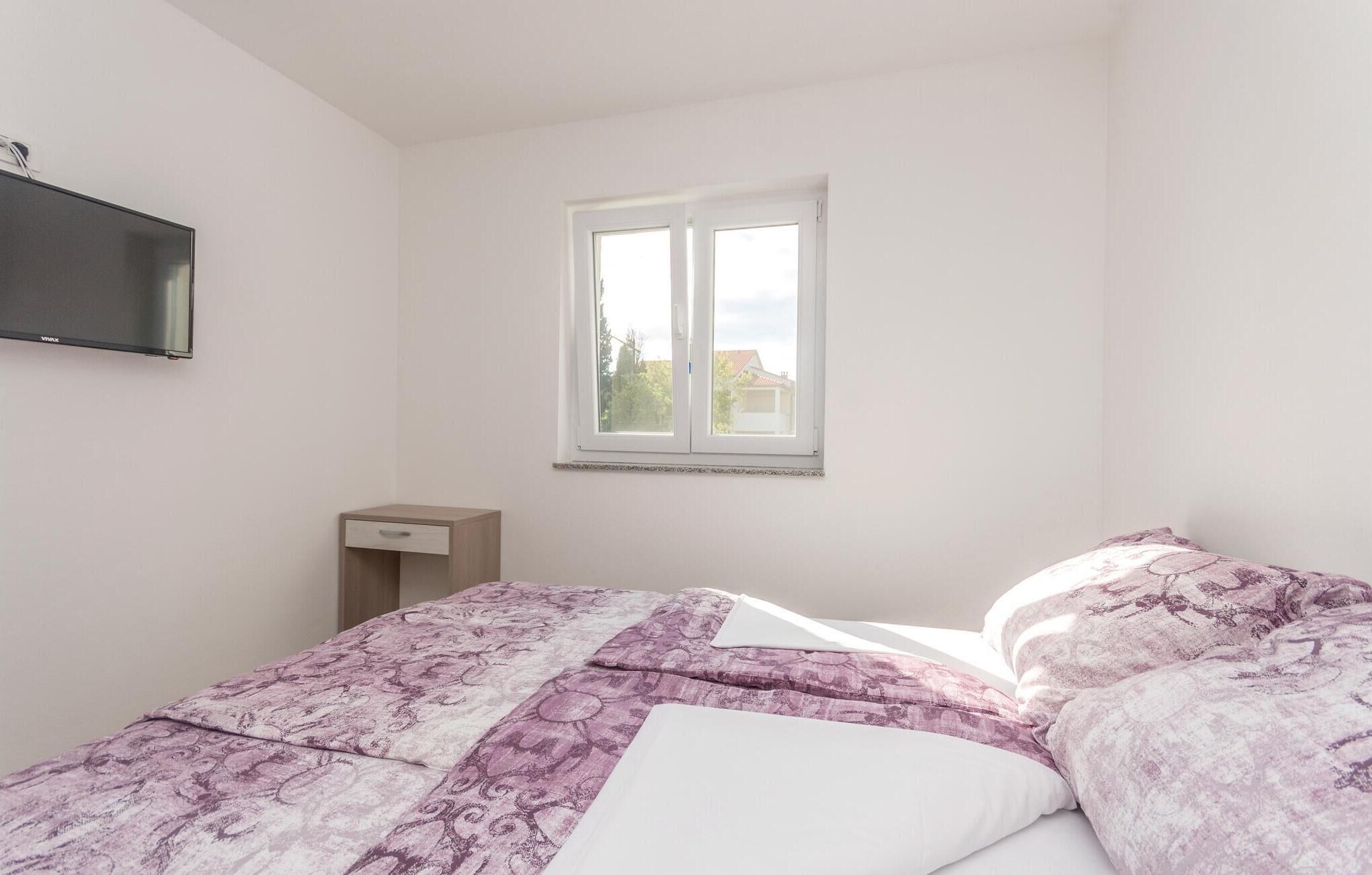 Une chambre à coucher avec un lit, une table de chevet, une télévision et une fenêtre.