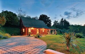 Experience the comfort of a cozy cabin with large windows and a covered porch, set amidst lush greenery.