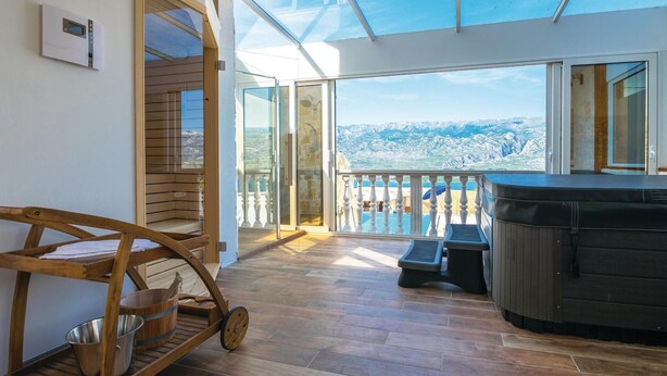 A balcony with a wooden swing chair, a hot tub, and a view of a mountainous landscape. - Beautiful home in Vinjerac with sauna (Vinjerac)