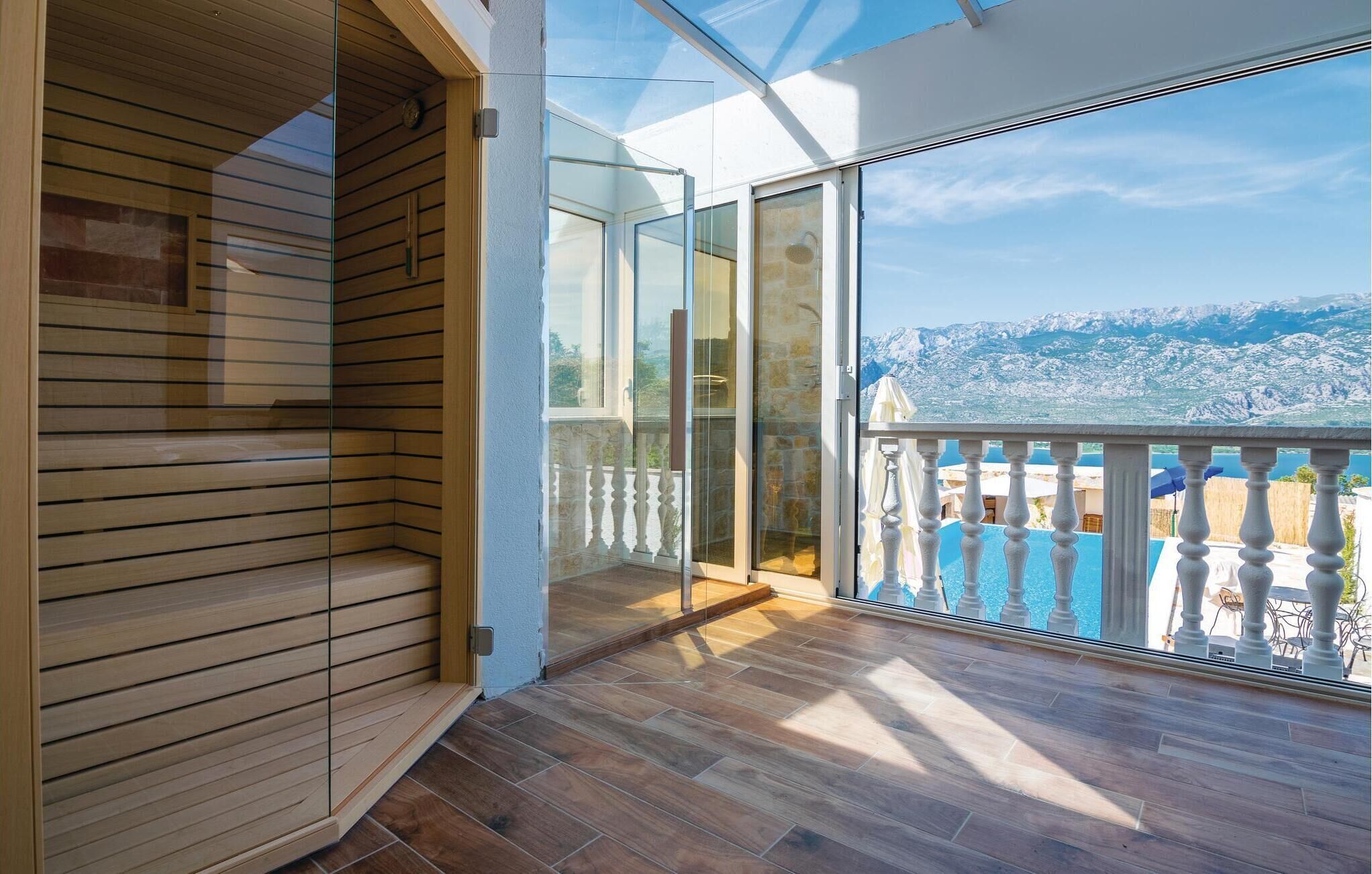 Un balcón con piso de madera y puertas de vidrio que dan a un área de piscina, con vista a un paisaje montañoso.