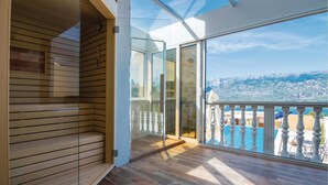 A balcony with a wooden floor and glass doors leading to a pool area, overlooking a mountainous landscape. - Beautiful home in Vinjerac with sauna (Vinjerac)