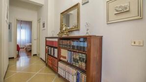 A hallway with a wooden bookshelf filled with books, a large mirror on the wall, and framed pictures. - Awesome apartment in Rapallo (GE) (Rapallo (GE))