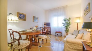 A dining area with a round table, chairs, and a television. There is a sofa and a lamp in the living area. - Awesome apartment in Rapallo (GE) (Rapallo (GE))