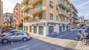 A multi-story residential building with balconies, parked cars, and a motorcycle. - Awesome apartment in Rapallo (GE) (Rapallo (GE))