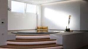 Een modern interieur met een rond zitgedeelte, een trap met verlichte treden en een minimalistische inrichting.