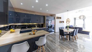 Een moderne keuken met donkere kastjes, een houten aanrecht en een eethoek met een ronde tafel en stoelen.