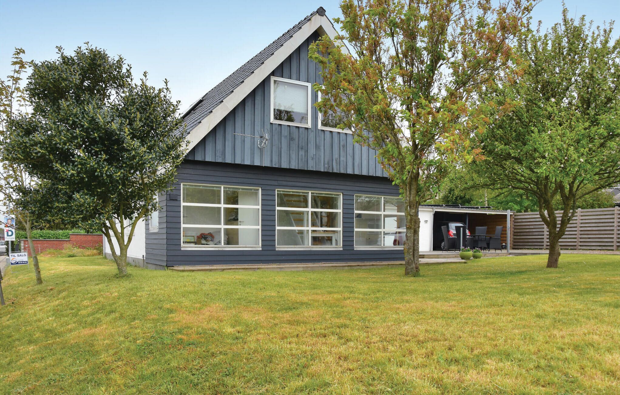 Une maison moderne à deux étages, dotée d’un garage, de grandes fenêtres et d’une pelouse bien entretenue.
