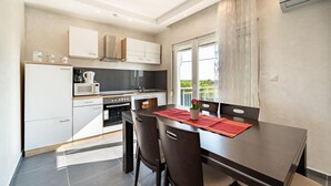 A modern kitchen with white cabinets, a microwave, and a stove. There is a dining table with chairs and a red placemat. - Awesome home in Islam Latinski (Islam Latinski)