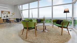 A spacious room with large windows, a round table, and green chairs.