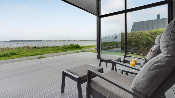 A modern outdoor seating area with a view of a lake and distant land.
