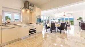 A modern kitchen with a central island, stainless steel appliances, and a view of the outdoors. - Stunning home in Sinj (Sinj)