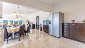 A modern kitchen with a large refrigerator, dark wooden cabinets, and a dining area with a table and chairs. - Stunning home in Sinj (Sinj)