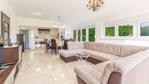 A spacious living area with a large beige sectional sofa, a dining table with chairs, and a kitchen in the background. - Stunning home in Sinj (Sinj)