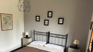 A bedroom with a bed, a nightstand, a lamp, and framed pictures on the wall. - Villa Rina - relaxing vacations in the hills with beautiful pool exclusively (Avola)