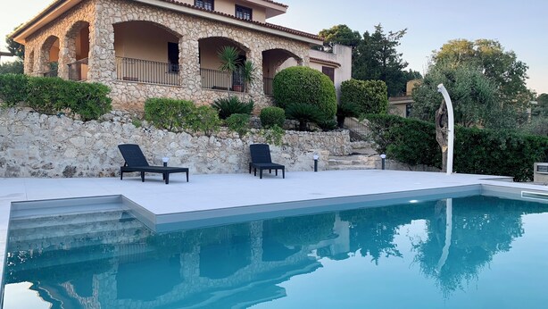 A poolside area with a stone building, two lounge chairs, and a clear blue pool. - Villa Rina - relaxing vacations in the hills with beautiful pool exclusively (Avola)
