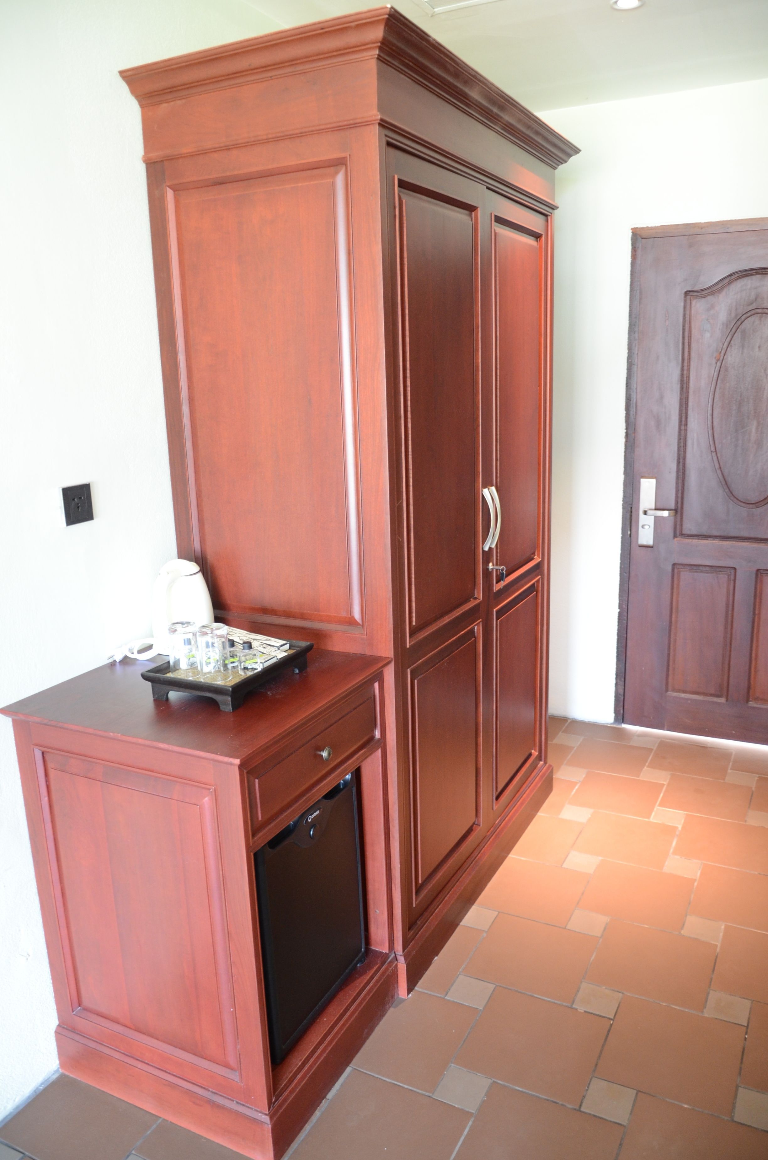 A wooden cabinet with drawers and a small built-in refrigerator.