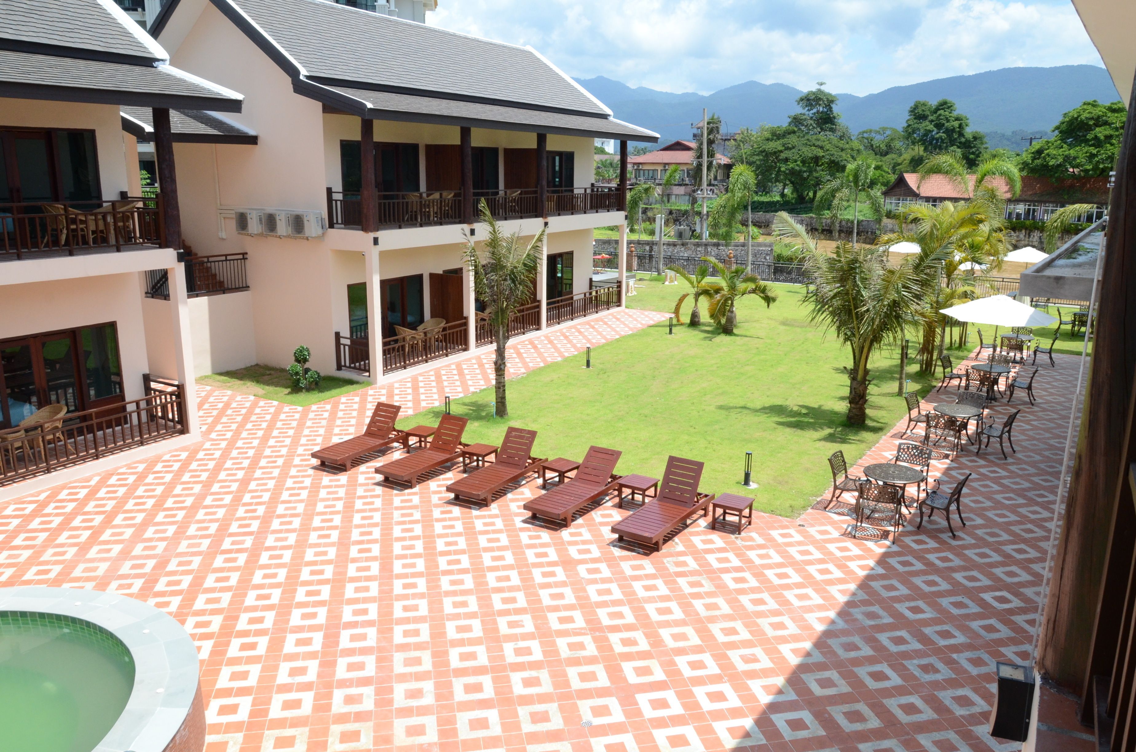 A hotel courtyard with a patterned floor, lounge chairs, and a pool.