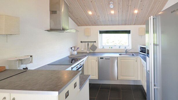 A modern kitchen with white cabinets, stainless steel appliances, and a black tiled floor. - 3 bedroom nice home in Vestervig (Vestervig)