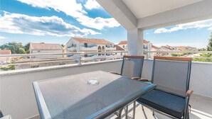 Ein Balkon mit zwei Stühlen und einem Tisch, mit Blick auf ein Wohngebiet mit Häusern und einer Straße.